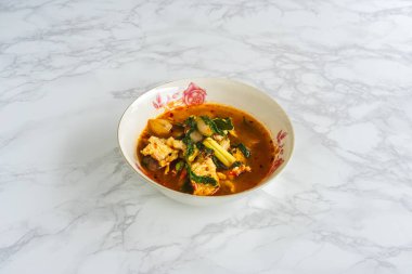 Baharatlı timsah çorbasının beyaz kasede mermer arka planda üst görüntüsü. Tayland baharatlı Tom çorbası, Tayland mutfağından. Sebzeli timsah eti sıcak çorba. Geleneksel Asya çorbası.