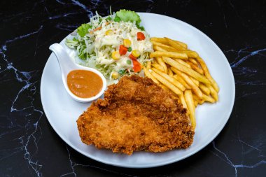 Biber soslu biftek, patates kızartması ve siyah mermer arka planda sebze salatası. Et bifteği ve patates kızartması hazır yemek servisi. Lezzetli biftek seti..