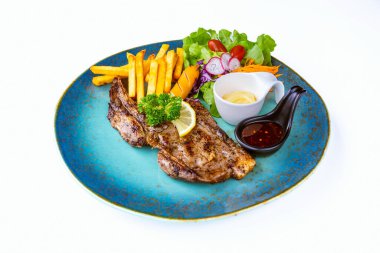 Biber soslu domuz pirzolası, patates kızartmalı sosis ve beyaz arka planlı sebze salatası. Et bifteği ve patates kızartması hazır yemek servisi. Biftek hazır.