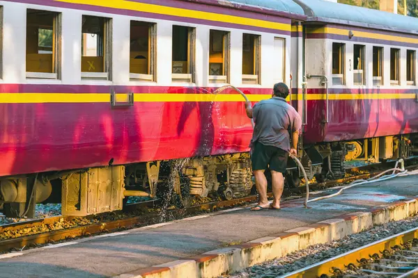 Erkek hademe, trenin dışını temizleyip yıkıyor. Tren istasyonunda treni temizleyen işçiler planlanan kalkıştan önce. Turist tatili için temizlik personeli temizlik treni.