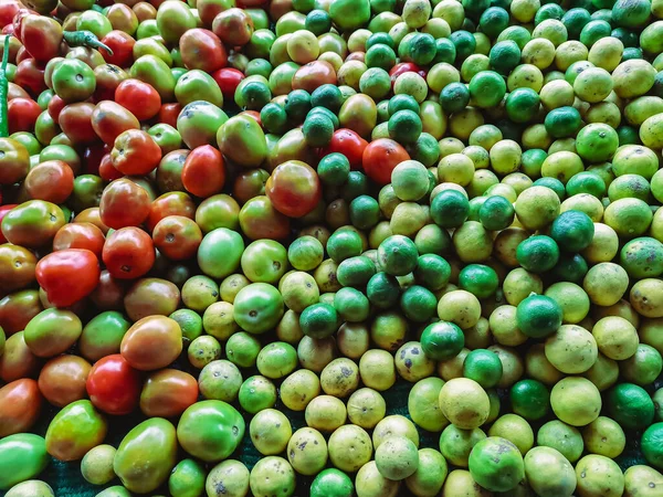 Markette satılmak üzere toplanan yeşil ve sarı limonlu çeşitli taze kırmızı ve sarı renkli organik domateslerin görüntüsü. Ürün canlı renktedir. Satılık taze meyve ve sebzeler..