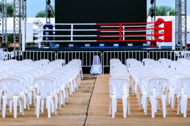 Boxing ring and many chairs for spectators prepared for competition, Outdoors. Sport and empty boxing ring in the city for a wrestling competition for athletes or boxers. Boxing ring with white seats. clipart