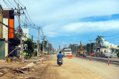 KANCHANABURI, THAILAND - 9 Eylül 2020: Thamuang Bölgesi 'nde karayolu inşaatı ve parlak turuncu trafik konileri ve kamyonları ile trafik sıkışıklıkları ve kazıcı veya kepçe yükleyici görülebiliyor.