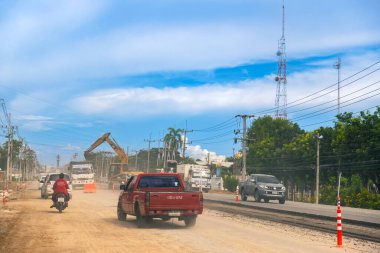 KANCHANABURI, THAILAND - 9 Eylül 2020: Thamuang Bölgesi 'nde karayolu inşaatı ve parlak turuncu trafik konileri ve kamyonları ile trafik sıkışıklıkları ve kazıcı veya kepçe yükleyici görülebiliyor.