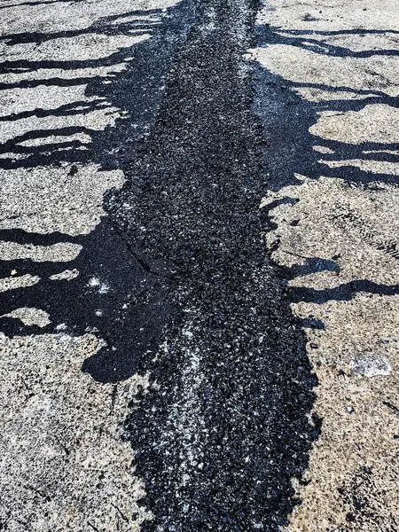 stock image Asphalt on road. Street with black tar filling the cracks. Cracks in concrete surface are then filled with asphalt. Texture of old asphalt road. Asphalt is covered with cracks, which filled with tar.