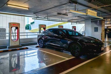 BANGKOK, THAILAND - 15 Nisan 2024: Siyah renkli Tesla elektrikli araba ICONSIAM 'ın park yerindeki Tesla Supercharger İstasyonu' na park edildi. Supercharger elektrikli araçlar için hızlı şarj teklif ediyor.