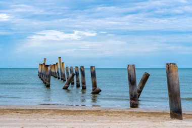 Eski iskelenin yaslanmış sütunlarının güzel manzarası. Eğik beton kutup plajı. Terk edilmiş balıkçı iskelesi, deniz kenarında. Birçok eski beton sütun deniz tarafından sahile bırakıldı. Seçici odak.