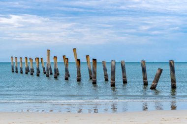 Eski iskelenin yaslanmış sütunlarının güzel manzarası. Eğik beton kutup plajı. Terk edilmiş balıkçı iskelesi, deniz kenarında. Birçok eski beton sütun deniz tarafından sahile bırakıldı. Seçici odak.