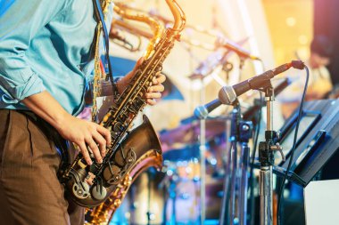 Bulanık arka planda saksafon çalan müzisyen. Arkadaşları olan bir adam müzik grubuyla saksafon çalıyor. Festivalde saksafoncu müzisyen tarafından çalınan müzik aleti. Seçici odak.