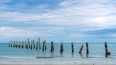 Eski iskelenin yaslanmış sütunlarının güzel manzarası. Eğik beton kutup plajı. Terk edilmiş balıkçı iskelesi, deniz kenarında. Birçok eski beton sütun deniz tarafından sahile bırakıldı. Seçici odak.