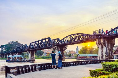 KANCHANABURI, THAILAND-FEBRUARY 9. 2019: Tanımlanamayan turistler 9 Şubat 2019 tarihinde Kanchanaburi, Tayland 'da bulunan Kwai Nehri üzerindeki Köprü' de gün batımından önce fotoğraf çekmeye geldiler.