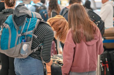 Havaalanı terminalinde bagaj kuyruğunda bekleyen insanlar. Girişte sıra bekleyen turistler var. Uçak biletlerini kontrol etmek için kuyruğa giren yolcular seyahat yolculuğuna çıkıyorlar..