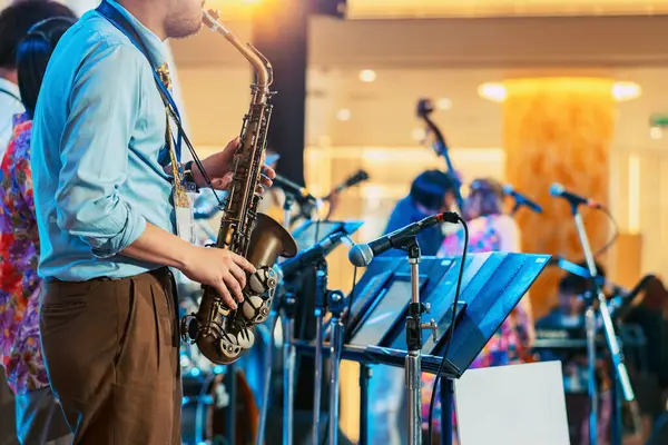 Bulanık arka planda saksafon çalan müzisyen. Arkadaşları olan bir adam müzik grubuyla saksafon çalıyor. Festivalde saksafoncu müzisyen tarafından çalınan müzik aleti. Seçici odak.