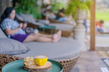 Sıcak kahve sarı fincanda ve gevrek nilüfer çiçeği kurabiyesi balkondaki tahta tahtada dinlenmek için.