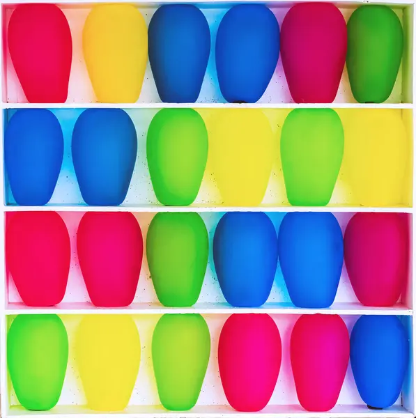 stock image Inflated balloons waiting to be popped sit on shelves of carnival game. Row of balloons ready to be explode by customers at a fun fair. Multi-colored inflatable balls in cells. Multi colored bubbles.