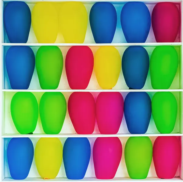 stock image Inflated balloons waiting to be popped sit on shelves of carnival game. Row of balloons ready to be explode by customers at a fun fair. Multi-colored inflatable balls in cells. Multi colored bubbles.