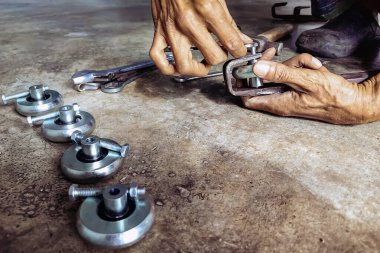 Kıdemli bir tamircinin elleri ve esnetilmiş çelik kapının sürgülü raylarında yeni tekerlekler. Sürgülü kapılara yeni çelik tekerlekler takıldı. Sürgülü kapı donanımı. Sürgülü kapıların ayarlanması