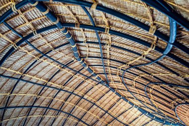 Çelik çubuklarla sazdan yapılmış samanlı ve karışık malzeme desenli bir yapı..