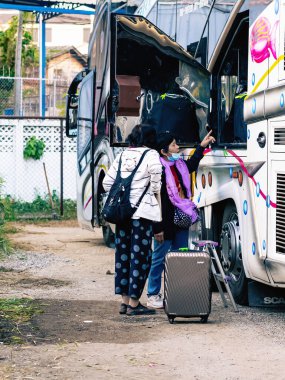 NAN-THAILAND, 12 Aralık 2020: Tanımlanamayan Tayland 'lı kadın turistler seyahat otobüsüne bindirip arkadaşlarıyla Cevaraj Hotel' in önünde seyahat etmek için bekliyorlar. Bavulları ve gezici otobüsleri hazırlayın..