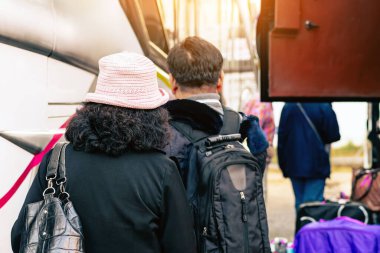 Otobüs durağındaki yaşlı mutlu turist çiftin arka görüntüsü. Mutlu aşıklar tatilde otobüsle seyahat ederek rahatlıyor ve eğleniyor. İstasyonda şapkalı bir kadın otobüse biniyor. İyi yolculuklar..