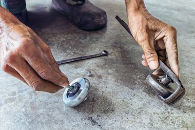 Kıdemli bir tamircinin elleri ve esnetilmiş çelik kapının sürgülü raylarında yeni tekerlekler. Sürgülü kapılara yeni çelik tekerlekler takıldı. Sürgülü kapı donanımı. Sürgülü kapıların ayarlanması