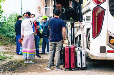 NAN-THAILAND, 12 Aralık 2020: Tanımlanamayan Tayland turistleri seyahat otobüsüne bindirip arkadaşlarıyla Cevaraj Hotel 'in önünde seyahat etmek için bekliyorlar. Bavullarınızı toplayın ve gezi otobüsüne binin..