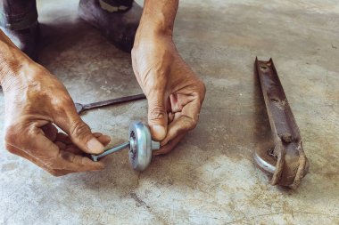 Kıdemli bir tamircinin elleri ve esnetilmiş çelik kapının sürgülü raylarında yeni tekerlekler. Sürgülü kapılara yeni çelik tekerlekler takıldı. Sürgülü kapı donanımı. Sürgülü kapıların ayarlanması