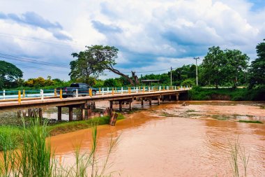 Şiddetli yağmur ve selden sonra ormandan gelen toprak ve çamur nedeniyle güçlü kirli su ile birlikte akan yabani otlar ve molozlar ile sulama kanalının görüntüsü. La Nina krizi, Su kirliliği.