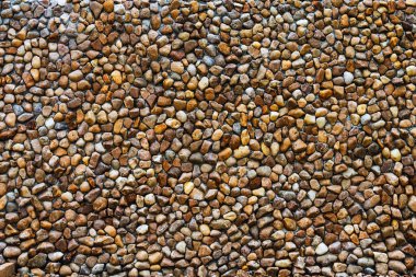 Güzel ve güçlü duvarı süslemek için düzenlenmiş büyük doğal çakıl taşları. Sarı ve kahverengi çakıl taşı duvar. Yuvarlak taş duvarın yüzey ve doku arka planı duvar kağıdı olarak kullanılacak. Bir sürü doğal taş..