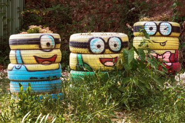 MUI NE, VİETNAM - 25 Nisan 2019: Eski istiflenmiş lastiklerden yapılan saksı Vietnam 'da popüler bir doğa turizmi merkezinde Minion çizgi film karakteri şekline boyandı.