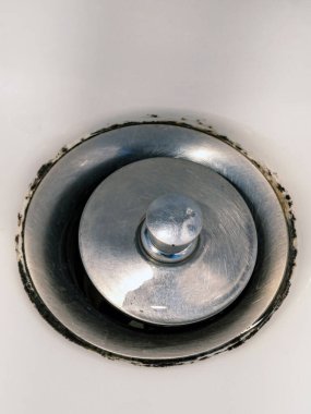 Lağım giderinde yosun arkaplanlı pis rögar kapağına yakın. Lavaboda paslanmaz çelik lavabo tıkaçı var. Banyoda lavabo var. Lichen lekeleri ya da küf lekeleri kirli banyoda ortaya çıkar..