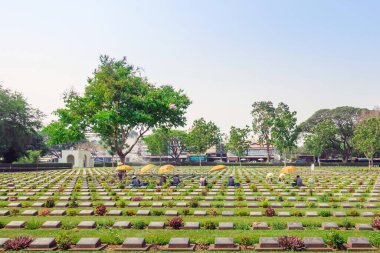 KANCHANABURI THAILAND - 21 Şubat: Kimliği belirsiz işçiler, 21 Şubat 2020 'de Kanchanaburi, Tayland' daki Kanchanaburi Müttefik Savaş Mezarlığı 'nda çiçek yenileyip dekore ediyorlar