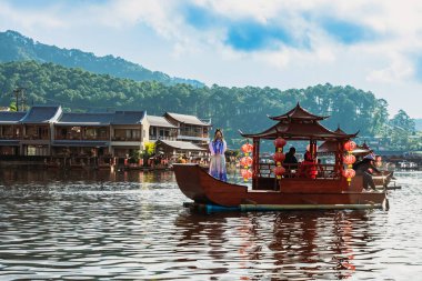 MAE HONG SON, THAILAND-DECEMBER 31,2024: Rak Thai Village Reservoir ya da Baan Rak Thai 'nin turistlerle dolu güzel manzarası ve antik Yunnan Çin tarzında bir göl manzaralı ahşap tekne alın