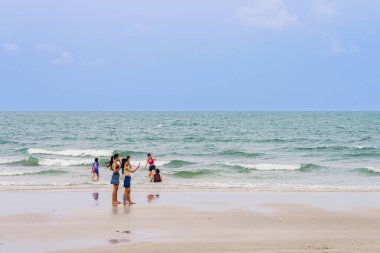 HUA HIN, THAILAND-MARCH 9.2024: Kimliği belirsiz genç, kaygısız kadın arkadaşlarının cep telefonu kullanmaları ve Hua Hin plajında fotoğraf çekmeleri. Seyahat, turizm ve tatil kavramı.
