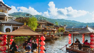 MAE HONG SON, THAILAND-DECEMBER 31,2024: Rak Thai Village Reservoir ya da Baan Rak Thai 'nin turistlerle dolu güzel manzarası ve antik Yunnan Çin tarzında bir göl manzaralı ahşap tekne alın