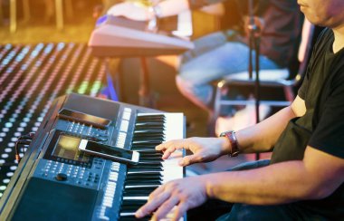 Müzisyen, konser sahnesinde çalmak için akıllı telefonu kılavuz olarak kullanarak elektronik klavye sentezleyicileri çalar. Akıllı telefona seçici odaklanma.