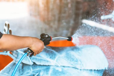 Otomatik para ile çalışan oto yıkama makinesinde motosikletini ya da motosikletini yıkayan mutlu bir kadın. Su ve köpükle oto yıkamada motosiklet temizlemek. Ellere seçici odaklanma.