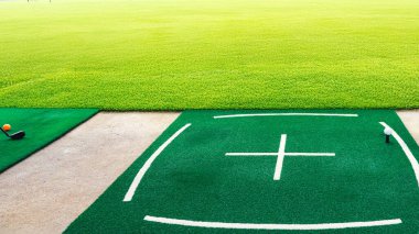 Golf topu golf sahasında paspaslara vuruyor. Golf antrenman sahası. Golf Vuruşu Matat 'ı. Çok güzel çitleri olan bir paspas. Naylon Tee Mat Golf Eşleri.