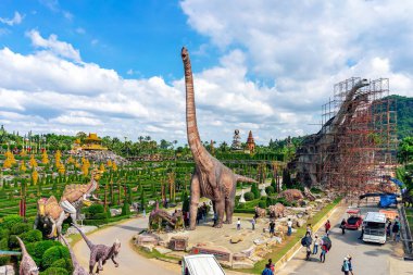 PATTAYA, THAILAND-DECEMBER 30. 2018: Nong Nooch Tropikal Botanik Bahçesi 'ndeki canlı benzeri manzaraya karşı heykeli veya çeşitli gerçekçi dinozor heykeli olan dinozor vadisi.