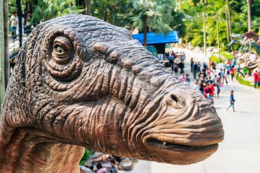 PATTAYA, THAILAND-DECEMBER 30. 2018: Nong Nooch Tropikal Botanik Bahçesi 'ndeki canlı benzeri manzaraya karşı heykeli veya çeşitli gerçekçi dinozor heykeli olan dinozor vadisi.