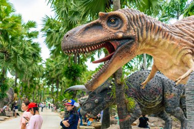 PATTAYA, THAILAND-DECEMBER 30. 2018: Nong Nooch Tropikal Botanik Bahçesi 'ndeki canlı benzeri manzaraya karşı heykeli veya çeşitli gerçekçi dinozor heykeli olan dinozor vadisi.