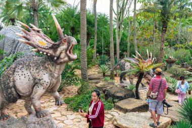 PATTAYA, THAILAND-DECEMBER 30. 2018: Nong Nooch Tropikal Botanik Bahçesi 'ndeki canlı benzeri manzaraya karşı heykeli veya çeşitli gerçekçi dinozor heykeli olan dinozor vadisi.