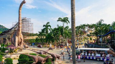 PATTAYA, THAILAND-DECEMBER 30. 2018: Nong Nooch Tropikal Botanik Bahçesi 'ndeki canlı benzeri manzaraya karşı heykeli veya çeşitli gerçekçi dinozor heykeli olan dinozor vadisi.