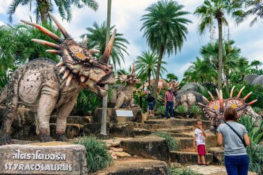 PATTAYA, THAILAND-DECEMBER 30. 2018: Nong Nooch Tropikal Botanik Bahçesi 'ndeki canlı benzeri manzaraya karşı heykeli veya çeşitli gerçekçi dinozor heykeli olan dinozor vadisi.