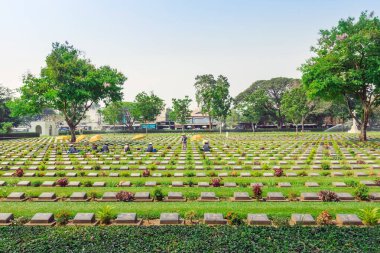 KANCHANABURI THAILAND - 21 Şubat: Kimliği belirsiz işçiler, 21 Şubat 2020 'de Kanchanaburi, Tayland' daki Kanchanaburi Müttefik Savaş Mezarlığı 'nda çiçek yenileyip dekore ediyorlar