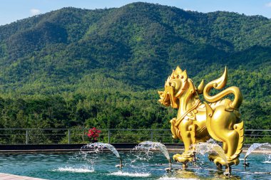 RATCHABURI, THAILAND - 17 Kasım 2018: Suanphueng Highland Garden 'daki havuz ve tepenin olduğu altın singha heykeli veya heykeli. Singha sembolü Asya tarafından kutsaldır ve saygı görür..
