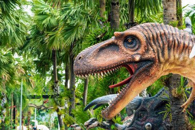 PATTAYA, THAILAND-DECEMBER 30. 2018: Nong Nooch Tropikal Botanik Bahçesi 'ndeki canlı benzeri manzaraya karşı heykeli veya çeşitli gerçekçi dinozor heykeli olan dinozor vadisi.