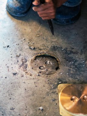 Su hizmetleri bakım servisinin yaşlı çalışanı evdeki kanalizasyon kanallarını değiştiriyor. Yaşlı adamın elleri kanalizasyon sisteminin lağım kapağını değiştirip onarıyor. Tuvalet drenaj sisteminin bakımı.