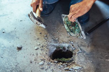 Su hizmetleri bakım servisinin yaşlı çalışanı evdeki kanalizasyon kanallarını değiştiriyor. Yaşlı adamın elleri kanalizasyon sisteminin lağım kapağını değiştirip onarıyor. Tuvalet drenaj sisteminin bakımı.