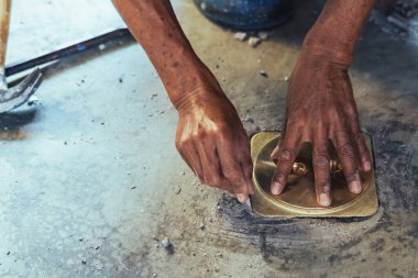 Su hizmetleri bakım servisinin yaşlı çalışanı evdeki kanalizasyon kanallarını değiştiriyor. Yaşlı adamın elleri kanalizasyon sisteminin lağım kapağını değiştirip onarıyor. Tuvalet drenaj sisteminin bakımı.